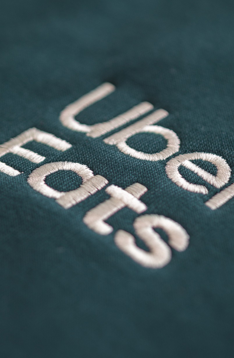 Close-up of cream chain-stitch embroidery on deep green fleece